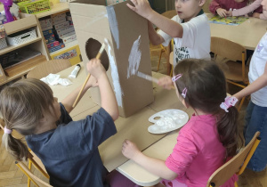 Dzieci malują białą farbą część rakiety.