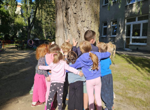 Dzieci przytulają się do drzewa.