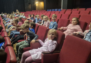 Dzieci siedzą w teatrze i czekają na spektakl.