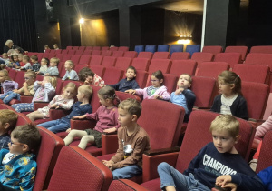 Dzieci siedzą w teatrze i czekają na spektakl.