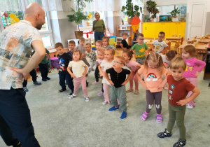 Dzieci rozgrzewają ciało przy muzyce naśladując prowadzącego.