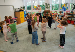 Dzieci przy dźwiękach muzyki naśladują ruchy instruktora tańca.