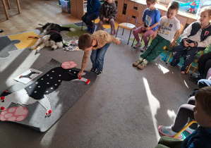 Dzieci zaznaczają czeronymi pomponikami gdzie nie można dotykać pieska.