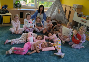 Dziewczynki i nauczycielka pozują do zdjecia na dywanie.