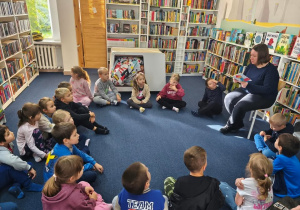 Dzieci słuchają opowiadania czytanego przez Panią bibliotekarkę.