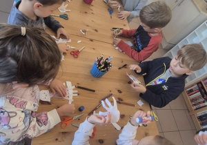 Dzieci siedzą na dywanie i słuchają opowiadania.