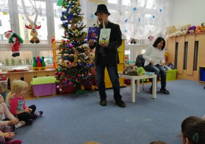 Dzieci siedzą na dywanie Poeta Eugeniusz Dolat prezentuje swoje ksiązki