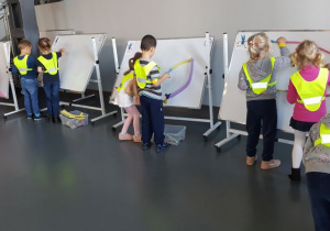 Dzieci podzielone na zespoły dwu osobowe tworzą na tablicach magnetycznych tunele dla kulek .