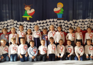 Pamiątkowe zdjęcie grupy. Dzieci w odświętnym ubraniu skupione w dwóch rzędach.