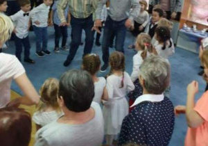 Dziadkowie w środku koła tańczą dla wnucząt.