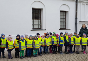 Grupa dzieci wraz z opiekunami stoi na dziedzińcu Białej Fabryki.