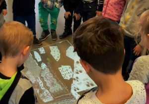 Dzieci stoją w kole na interaktywnej podłodze w muzeum.
