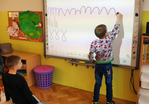 Chłopiec pisze na tablicy wskazany wzór .