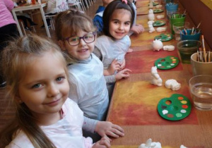 Dzieci stoją przy stole i zaczynają malować gipsowe figurki.