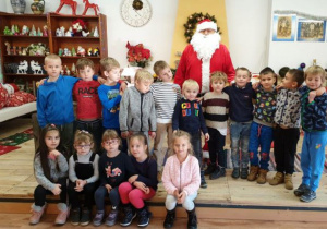 Dzieci ustawine w dówch rzędach, a za nimi stoi św. Mikołaj.