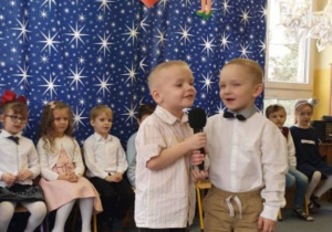 Dwóch chłopców recytuje wiersze do mikrofonu trzymanego w ręku.