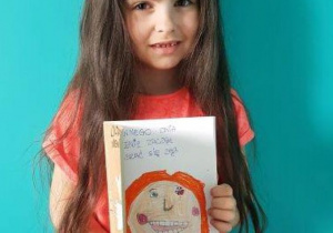 Dziewczynka trzyma w rękach swoją książkę, którą sworzyła w ramach tygodnia "Tajemnica książek.".