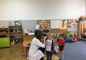 Dzieci czekają w kolejce na badanie do pani doktor.