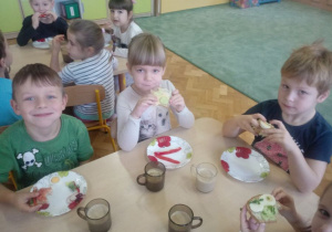 Z uśmiechem na twarzy dzieci jedzą śniadanie.