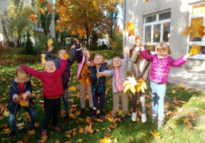Dzieci podrzucają liście.