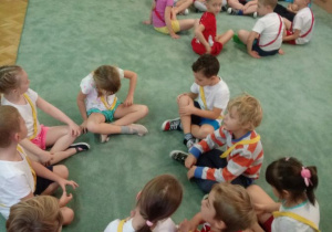Dzieci siedzą na dywanie w dwóch mniejszych kołach.