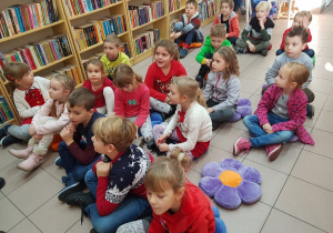 Dzieci uważnie słuchają opowiadania w bibliotece.