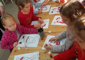 Dzieci kolorują kredkami elementy ubioru Św.Mikołaja.