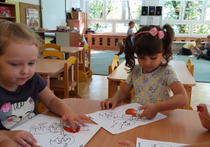 Nadia i Amelia malują farbami wizerunek mrówki.