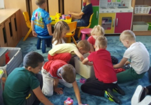 Dzieci bawią się na dywanie dowolnie wybraną przez siebie zabawką.