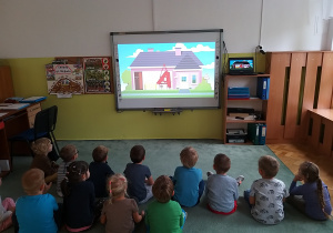 Dzieci oglądają na tablicy interaktywnej film edukacyjny.
