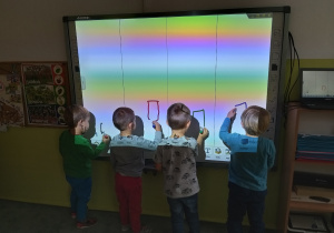 Dzieci rysują na tablicy interaktywnej.