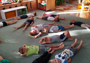 Dzieci leżą na plecach na dywanie.