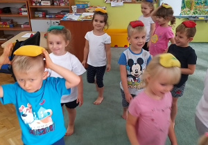 Dzieci próbują utrzymać równowagę, poruszając się z woreczkami ułożonymi na głowach.