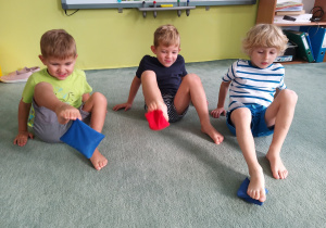 Dzieci unoszą woreczki stopami.