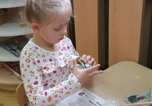 Dziewczynka robi kulkę z gazety i owijamy ją bibułą.