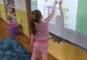 Dziecko odkrywa pola zgodne z współrzędnymi na tablicy interaktywnej.