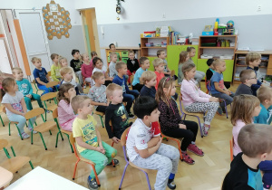 Dzieci siedzą na krzesełkach i ogladają spektakt Teatru Lalek.