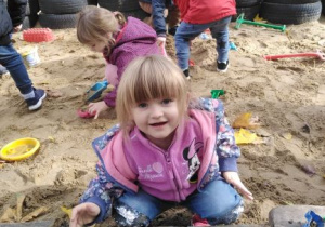 Dziewczynka tworzy babki z piasku.