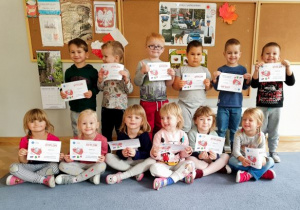 Dzieci ustawione w dwóch rzędach prezentują swoje dyplomy za udział w akcji Cała Polska Programuje.