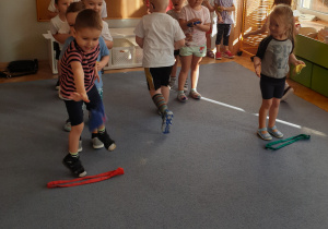 Dzieci ustawione w dwóch rzędach wykonują woreczkami rzuty do celu.