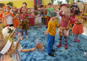 Dzieci w rytm muzyki poruszają uniesionymi w górę rękami.