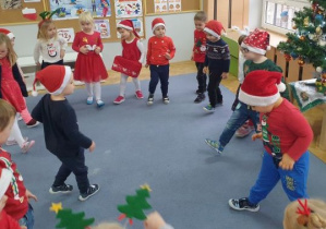 Dzieci wspólnie w kole tańczą przy rytmach świątecznych piosenek.