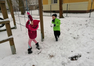 Lena wspina się na linę, a Olek próbuje rzucić w Lenę kulką ze śniegu