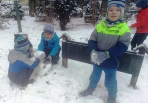 Czas na zimowe zabawy- dwaj chłopcy lepią bałwana, dwaj lepią śnieżne kule.