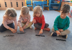 Zabawy matematyczne dzieci na dywanie przy użyciu guzików.