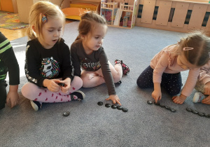 Dzieci układają wieże na dywanie.