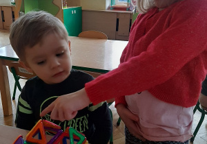 Dwójka dzieci układa budowlę z klocków magnetycznych.