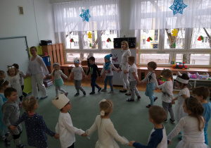Dzieci tańczą w koło w rytm piosenki.