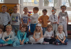 Dzieci ustawione w dóch rzędach prezentują swoje ubrania na Bal Zimy.