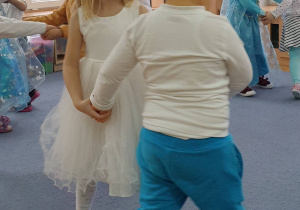 Dziewczynka i chłopiec tańczą w parze do piosenki zimowej.